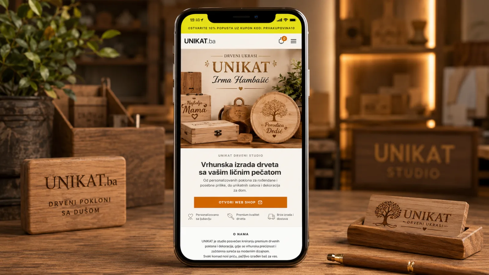 UNIKAT mobilna online prodavnica prikazana na iPhone uređaju u toplom ambijentu studija za izradu drvenih poklona